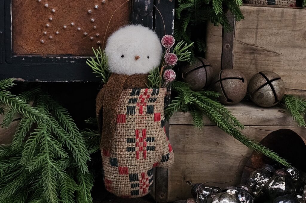 Handmade primitive snowman in vintage coverlet mitten, rustic farmhouse Christmas décor with wool scarf, berries, and pine sprigs