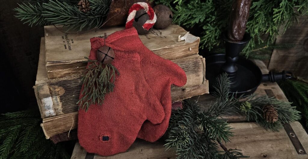 Handmade primitive Christmas mittens crafted from vintage red cotton fabric, rustic farmhouse holiday décor with jingle bell and candy cane accent