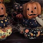 Primitive Jack‑O‑Lantern stack with Autumn Orange head on fabric cushions and real wood slice base.
