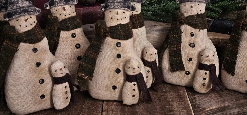 Primitive folk art snowman tuck with attached snow buddy, aged osnaburg fabric, wool scarves, painted hat, and rustic stitched details shown in full front view.