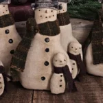 Primitive folk art snowman tuck with attached snow buddy, aged osnaburg fabric, wool scarves, painted hat, and rustic stitched details shown in full front view.