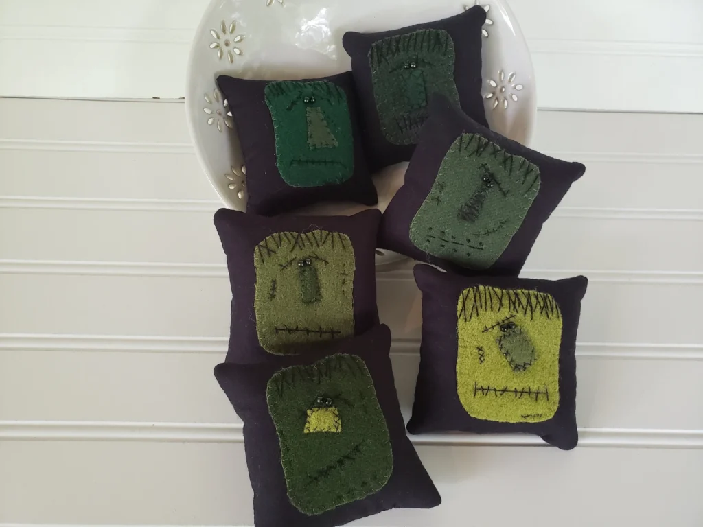 Primitive wool Frankenstein bowl fillers with stitched faces and black button eyes.