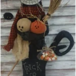 Primitive Halloween black cat doll dressed as a witch, holding a broom, pumpkin, ghost and candy corn bag, with stitched ‘Trick or Treat’ on the body.