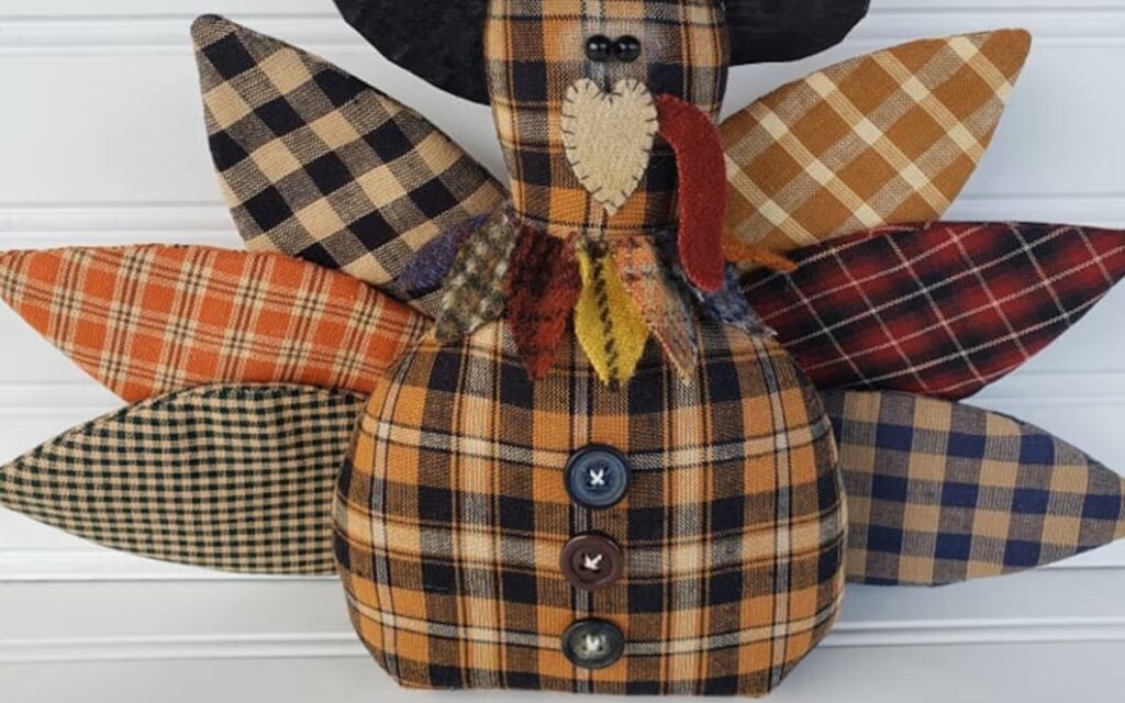 Close‑up of primitive homespun Thanksgiving turkey showing weighted boxed bottom, homespun fabrics, and rustic aged finish.