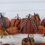 Close‑up of handmade homespun fabric pumpkin showing real wood stem, green tie, and wire tendrils