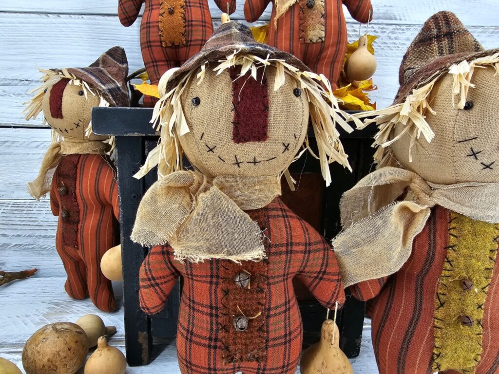 Close‑up of handmade scarecrow face with osnaburg fabric, stitched details, and aged primitive finish