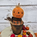 Primitive pumpkin shelf sitter with zig‑zag stitched mouth, aged osnaburg head, and real wood stem