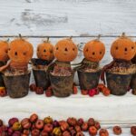 Handmade primitive pumpkins in faux rusty pots, each with aged osnaburg heads, wool scarves, and fall homespun bodies