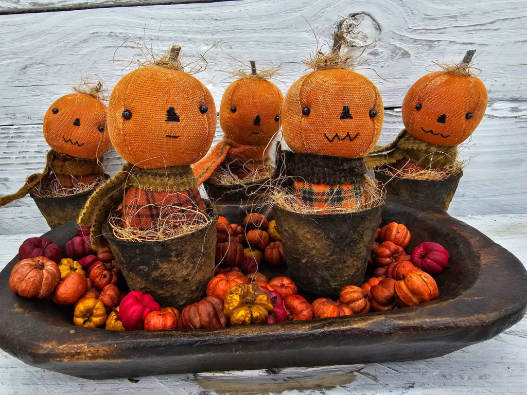 Group of primitive pumpkin shelf sitters in faux rusty pots with stitched faces, real stems, and homespun autumn fabrics
