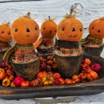 Group of primitive pumpkin shelf sitters in faux rusty pots with stitched faces, real stems, and homespun autumn fabrics