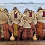 Group of primitive folk art scarecrow dolls with homespun bodies, wool noses, stitched faces, and fall gourd accents