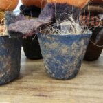 Close‑up of faux rusty pot painted black with cinnamon‑dusted aged finish and stuffed with fall straw