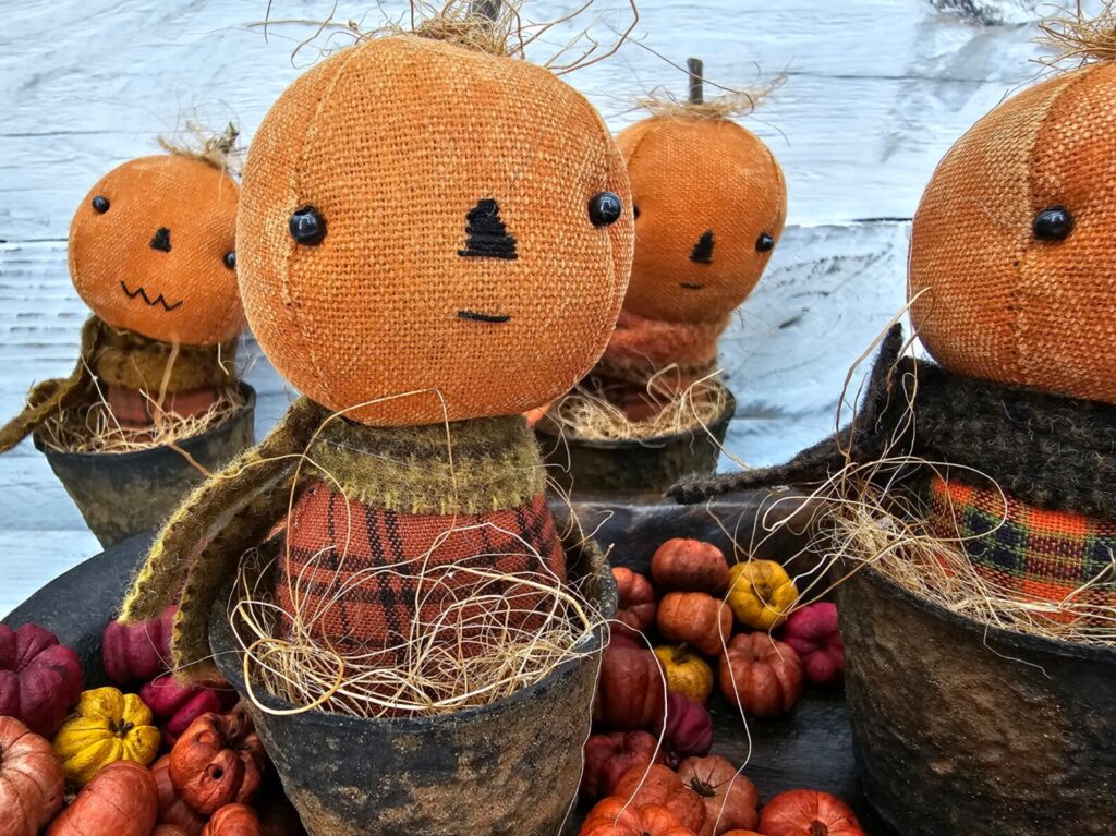 Group of a few primitive pumpkin shelf sitters in faux rusty pots with stitched faces, real stems, and homespun fall fabrics