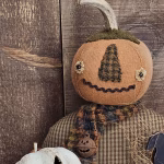 Close‑up of primitive pumpkin man Oliver showing stitched facial features, wool nose, bead eyes, and aged painted fabric.