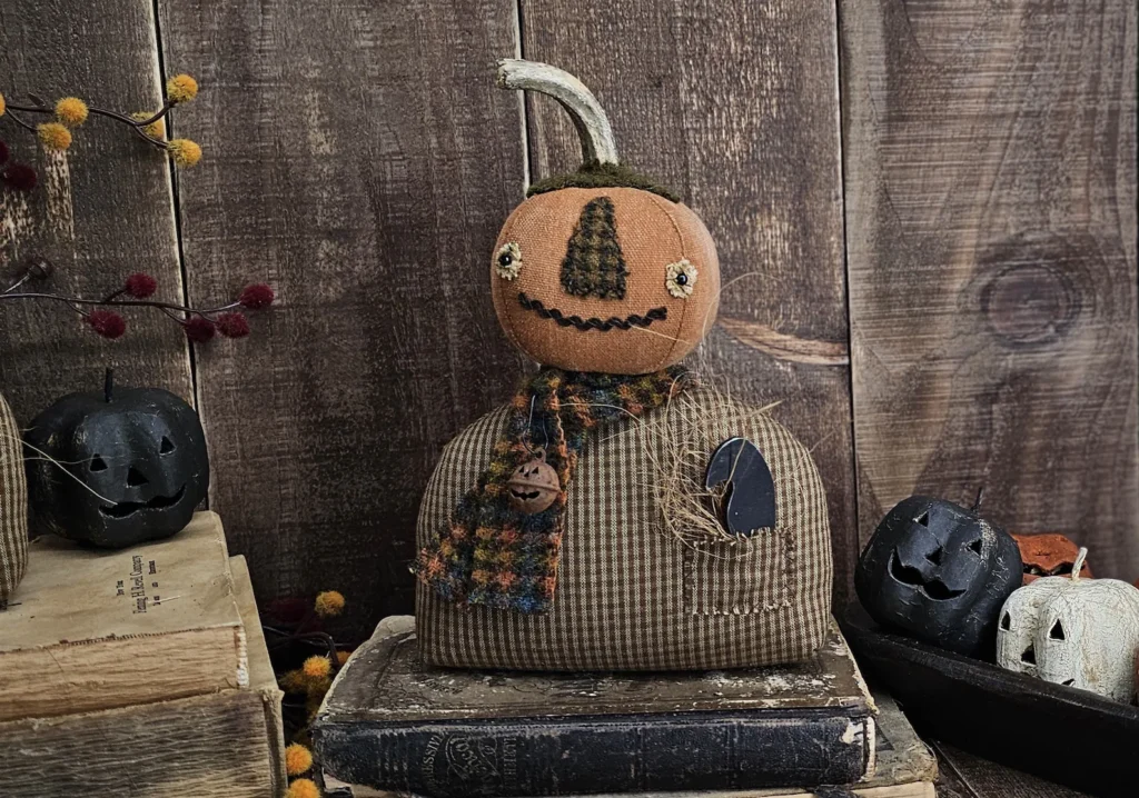 Handmade fall pumpkin shelf sitter with real stem, stitched face, and homespun body