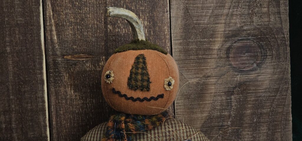 Rustic Halloween pumpkin man décor with wool nose, rick‑rack mouth, and removable crow