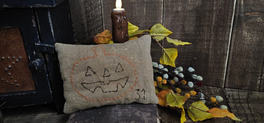 Primitive Jack O’Lantern pillow made from aged vintage linen with hand‑stitched face
