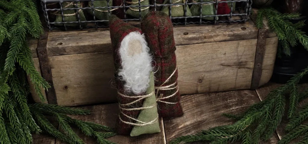 Back view of primitive wool Santa tuck showing needle‑felted wool hair, aged osnaburg body, and red wool sack.