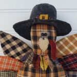 Close‑up of primitive homespun Thanksgiving turkey showing pilgrim hat, wool collar, and stitched facial details.
