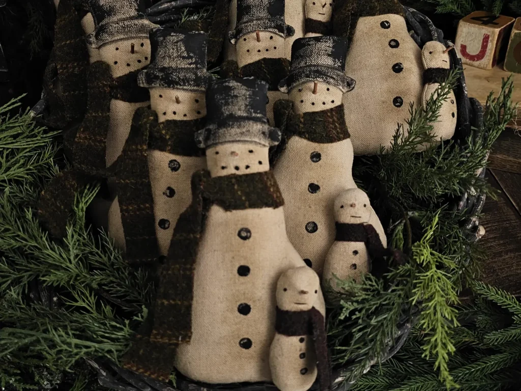 Primitive snowman tuck body with hand‑stitched details, wool scarves, and rustic painted accents.