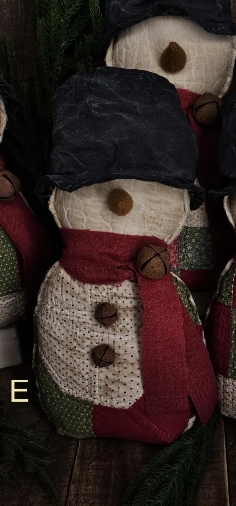 Primitive quilted snowman, Variant E, made from mixed vintage quilt colors and worn patchwork textures; letter E shown on photo.