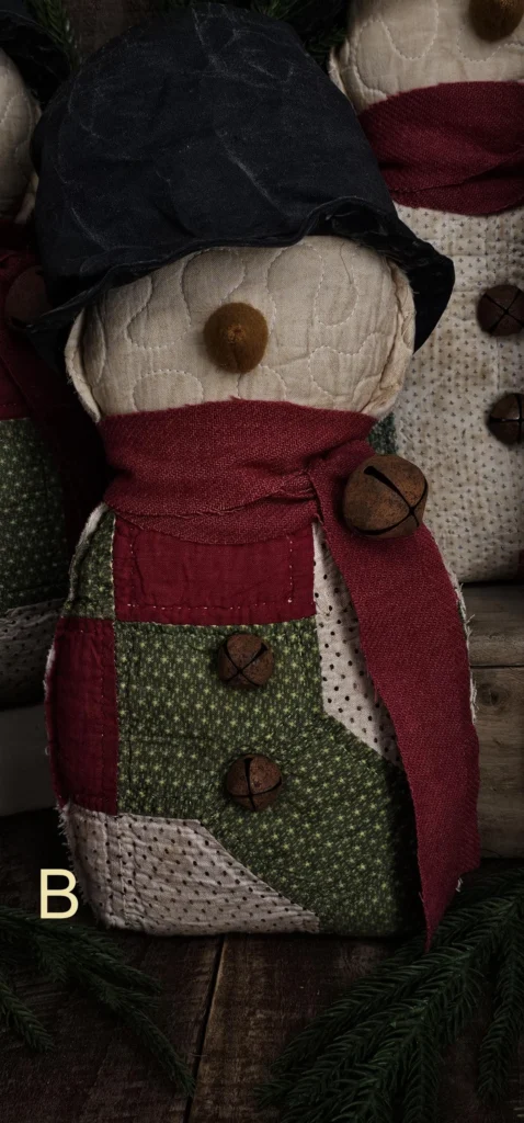 Primitive quilted snowman, Variant B, crafted from repurposed patchwork quilt with darker red and green sections; letter B visible on photo.