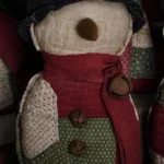 Primitive quilted snowman, Variant D, with bold red and green quilt pattern and aged fabric details; letter D visible on photo.