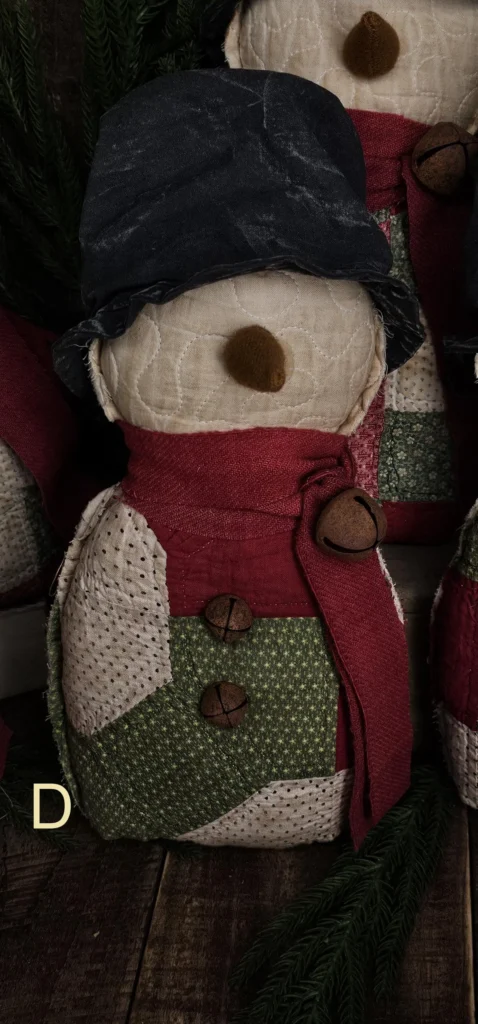 Primitive quilted snowman, Variant D, with bold red and green quilt pattern and aged fabric details; letter D visible on photo.