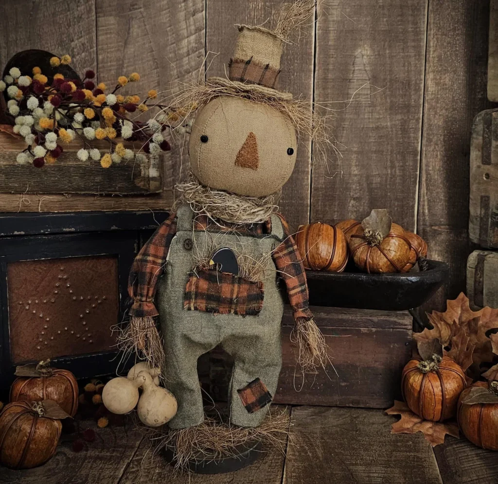 Primitive fall scarecrow doll with hand‑stitched face, gourds, and removable wooden crow.