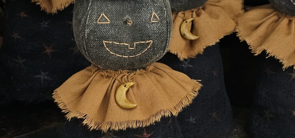 Close‑up of handmade aged clay moon necklace on primitive terracotta moon witch.