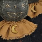 Close‑up of handmade aged clay moon necklace on primitive terracotta moon witch.