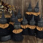 Primitive handmade moon witch with terracotta collar, clay moon necklace, star‑print body, and black witch hat for Halloween décor.